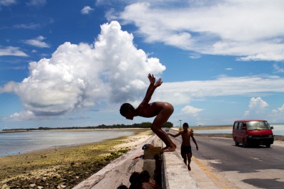 Boy jumping in the water from the causeway that separates the lagoon from the ocean on the island of Tarawa. ©Malin Fezehai
