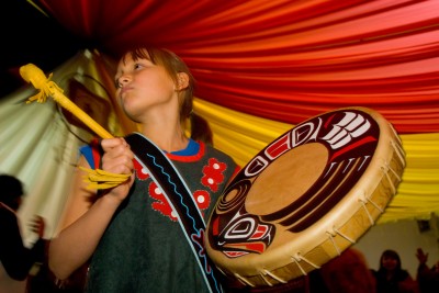 A young Tahltan girl beats a drum during celebrations of the 100th anniversary of the Tahltan Declaration, Telegraph Creek, Tahltan Nation, British Columbia
