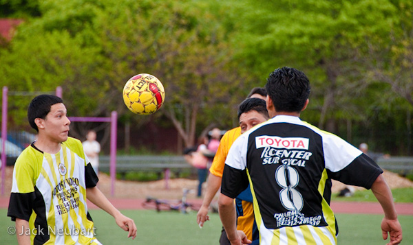 SPORTS. For this second shot, I cropped in a little to focus on the ball and players. Focal length remained constant, at 200mm (= 300mm). I should note that, even though the manual-focusing ring feels a bit gritty (typical of many AF lenses), I found I could easily focus using one or two fingers to rotate the ring while the same hand was supporting the lens. Photo Copyright  ©2009 Jack Neubart. All rights reserved.