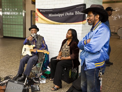 Indoor portrait. As I was heading toward my train, I came upon this very talented blues singer, so I grabbed the 5D Mark II with 16-35mm lens and composed the shot. The first image was made by available light (at 1/25 sec.-who need image stabilization?); flash was added for the second. If you're wondering why the performer is pointing at me, I was moving in for the shot and he noticed not me and the camera so much as my Tilley hat, which he obligingly incorporated into the song-to the amusement of the crowd. A little laughter at my expense, but it was worth it. Copyright  ©2009 Jack Neubart. All rights reserved.